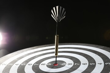 Targeting. Dart board with arrow on dark background, closeup
