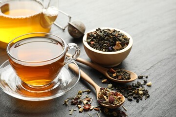 Delicious herbal tea and dry leaves on black table, closeup