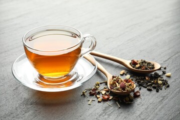 Delicious herbal tea and dry leaves on black table, closeup