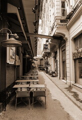 Outdoor Cafe Tables Empty Narrow Alley Sepia Urban Street Architecture Vintage Mood. Cozy Dining Spot Captured From Eye Level In Warm Sepia Tones