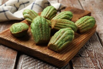 Tasty matcha madeleine cakes on wooden table, closeup