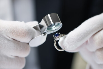 Fototapeta na wymiar Appraiser with loupe evaluating luxury ring, closeup