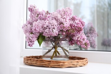 Beautiful lilac flowers in glass vase on window sill indoors