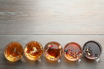 Aromatic herbal tea in glass cups on wooden table, flat lay. Space for text