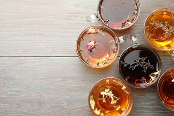 Aromatic herbal tea in glass cups on wooden table, flat lay. Space for text