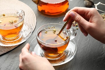 Woman with aromatic herbal tea at black table, closeup