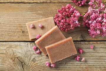 Soap bars and lilac flowers on wooden table, flat lay