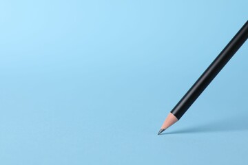 Sharp graphite pencil on light blue background, closeup. Space for text