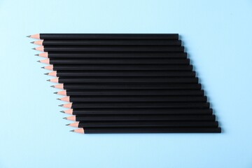 Many sharp graphite pencils on light blue background, flat lay