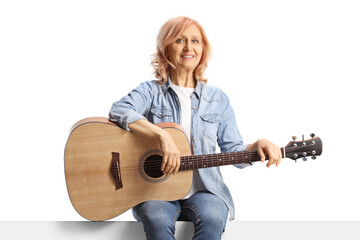 Woman sitting on a panel with an acoustic guitar