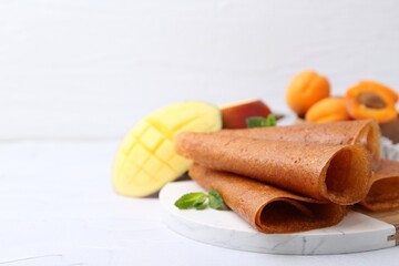 Delicious fruit leather rolls, mint, mango and apricots on white table, closeup. Space for text