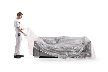 House painter covering a sofa with a plastic drop cloth