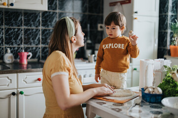 A mother and her toddler child spend time together in their kitchen. They enjoy preparing food,...