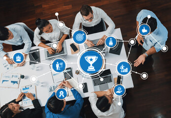 Aerial view of a diverse team collaborating in an office setting with digital icons representing success, strategy, and connectivity focused on achieving goals. Amity