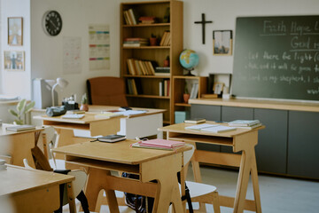 Classroom filled with desks and bookshelves highlighted by natural light from windows creating academic and peaceful atmosphere reflecting dedication to education and learning