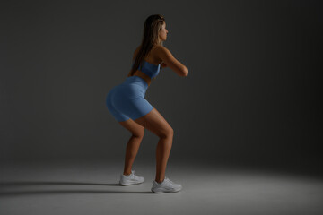 Fitness enthusiast performing squats in a minimalist studio setting during evening hours
