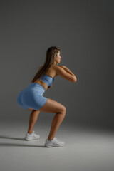 Fitness enthusiast performs squats in a modern studio setting during a workout session focused on...