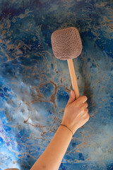 Hand holding a mallet poised to strike a gong set against a vibrant, abstract background. The scene capture the essence of gong meditation, focusing on sound and mindfulness