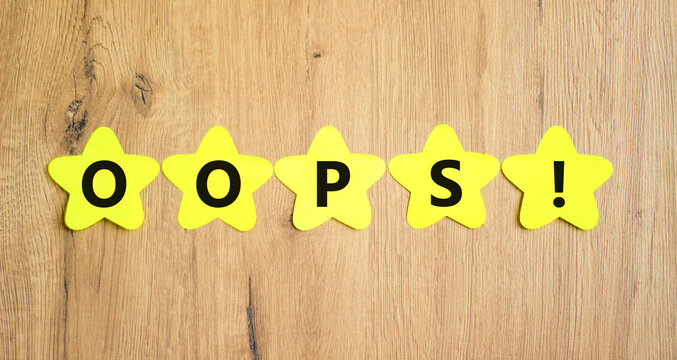 Oops symbol. Concept word Oops on beautiful yellow paper stars. Beautiful wooden table wooden background. Business lifestyle oops concept. Copy space.