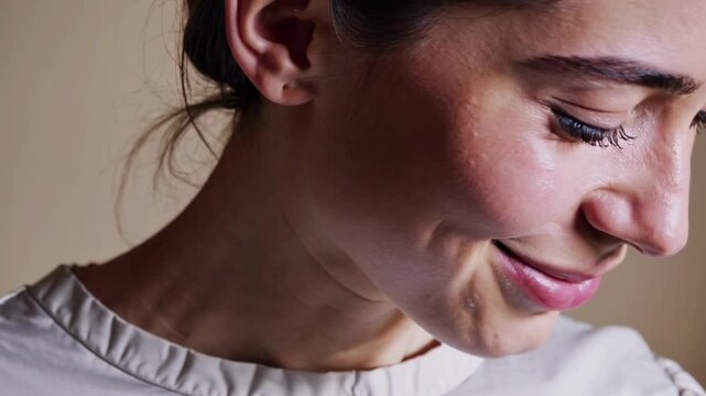 Close-up portrait of a woman smiling softly, captured at eye level. The video style emphasizes natural beauty and warm, soft lighting.