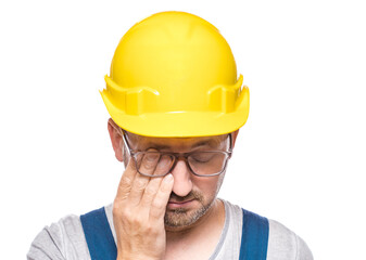 Tired construction worker rubbing eyes, isolated on white background. Exhausted repairman with closed eyes. Middle-aged construction worker covers face. Sleepy expression. Craftsman against white wall