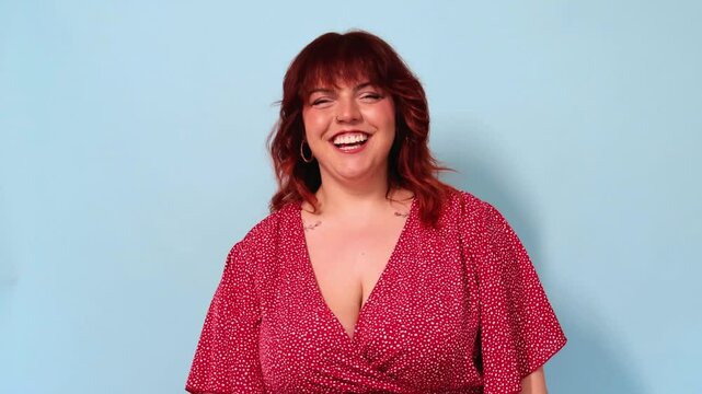 curvy Redhead woman laughing on blue background