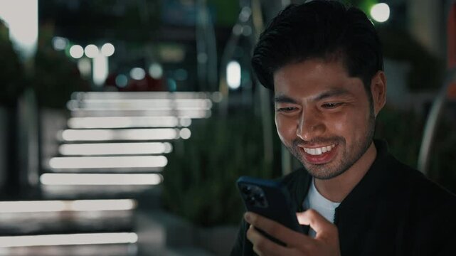 Portrait of excited asian man holding smartphone and making victory gesture while raising hands with clenched fist. Happy human checking mailbox and receiving message with victory offer.