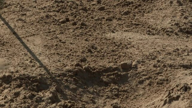 Close-up: Official uses a measuring tape tool to accurately determine the distance of an athlete's long jump attempt in a sand pit during a track competition.
