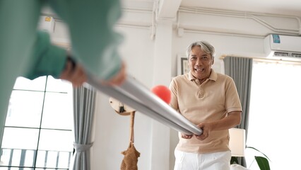 Obraz premium Grandfather holding pipe and carrying ball rolling game for exercise to improve eye, hand coordination or enhance focus and concentration. Elder couple providing stress relieve. Healthcare. Myrmidon.