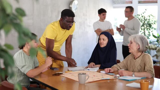 Group of multinational students of different years play a board game with passion