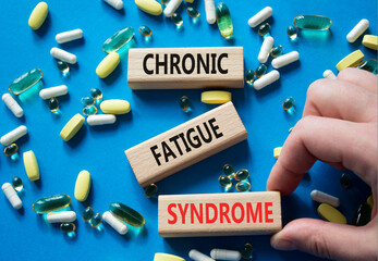 Chronic Fatigue Syndrome symbol. Concept word Chronic Fatigue Syndrome on wooden blocks. Doctor Hand. Beautiful blue background with pills. Medicine and Chronic Fatigue Syndrome concept. Copy space
