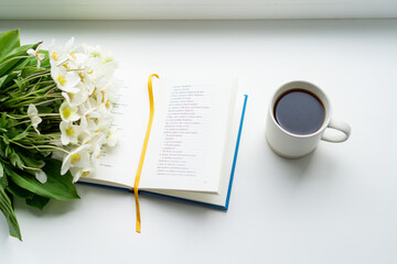 Beautiful summer still life on the windowsill. A bouquet of white flower Helleborus and a book on the windowsill in a cozy home.