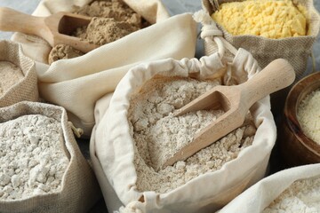 Different types of flour in bags on table, closeup