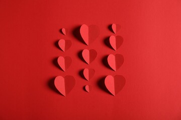 Many paper hearts on red background, flat lay