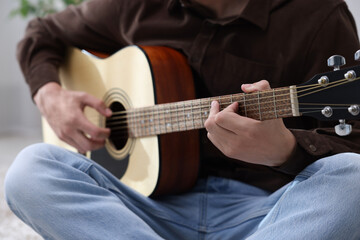 Fototapeta premium Man playing guitar on floor indoors, closeup