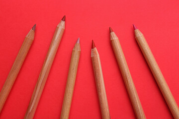 Different lip pencils on red background, flat lay