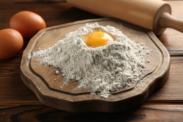 Pile of flour, eggs and rolling pin on wooden table, closeup