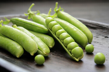Concept, fresh green peas laid out on a plate on a dark background.