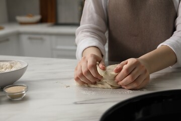 Making pretzels. Woman kneading dough at table in kitchen, closeup