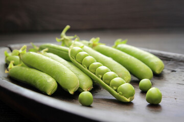 Concept, fresh green peas laid out on a plate on a dark background.
