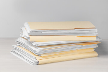 File folders with papers on wooden table against light background
