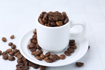 Aromatic coffee beans, cup and saucer on white table, closeup
