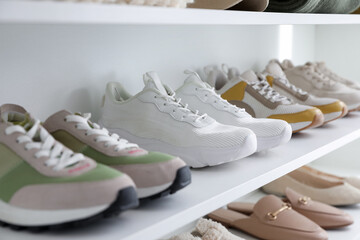 Different footwear on shelves indoors, closeup. Shoe storage