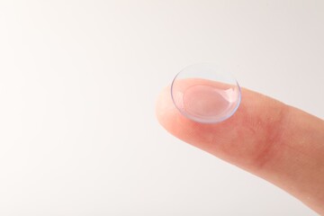 Woman with contact lens on light background, closeup. Space for text