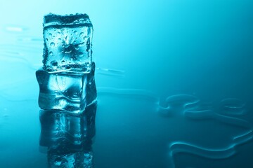 Cubes of clear ice on light blue background, space for text