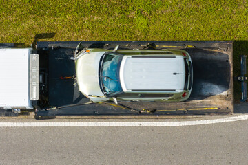 Car accident on American street. Tow truck picking up destroyed car and emergency services helping victims of vehicle crash on road in USA