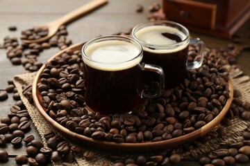 Aromatic coffee in cups and beans on wooden table, closeup