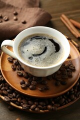 Aromatic coffee in cup, beans and cinnamon on table, closeup