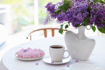 Bouquet of beautiful lilac flowers, coffee and dessert on white table indoors. Space for text