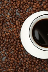 Aromatic coffee in cup on beans, top view